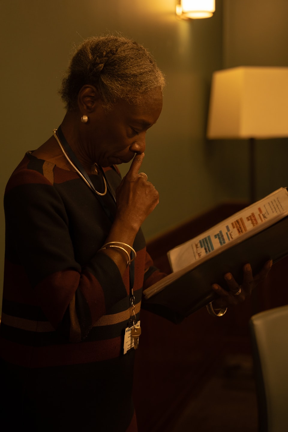 Woman in a striped sweater reviews documents in a binder.