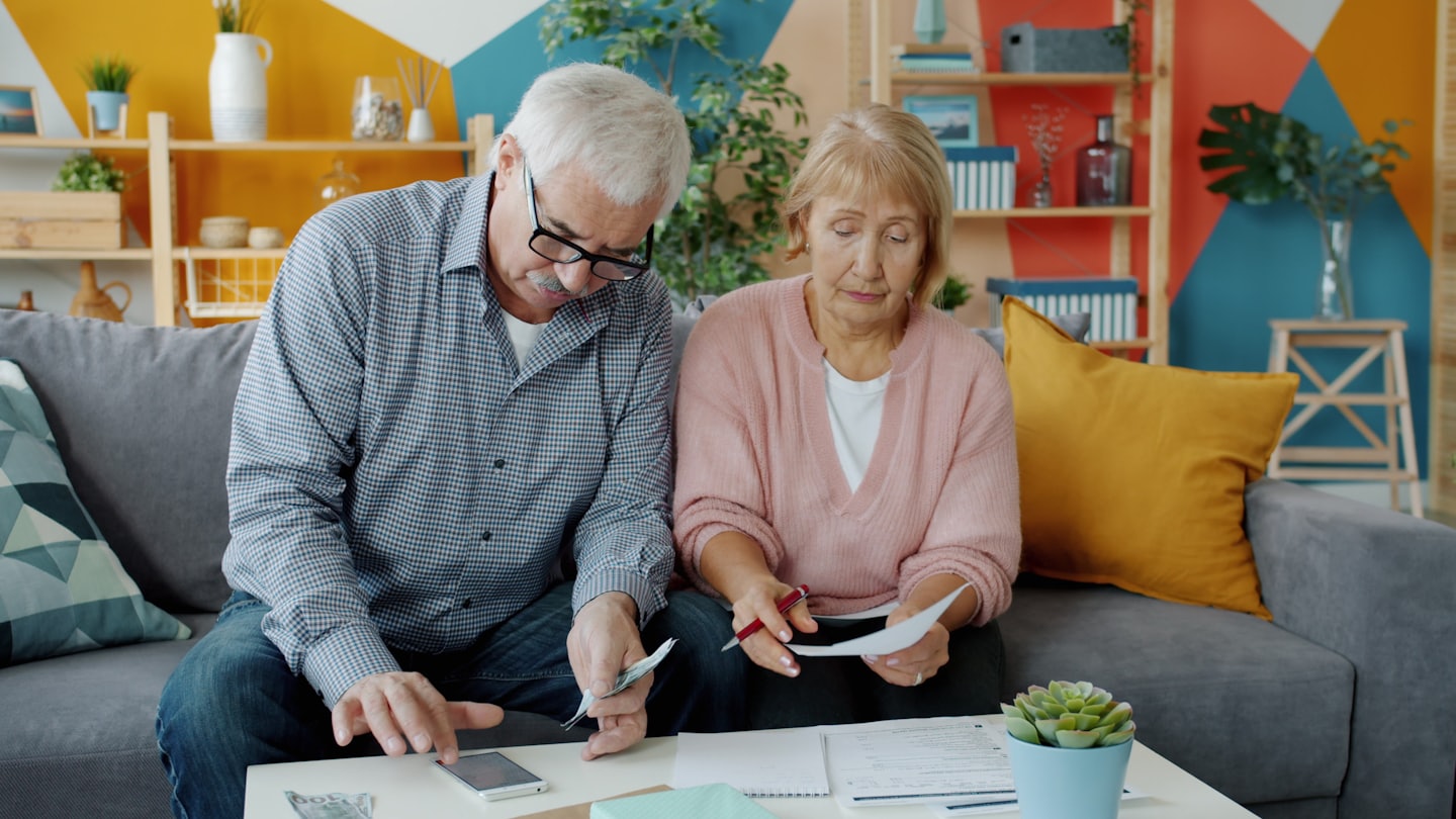 Couple reviewing documents and money on a sofa.
