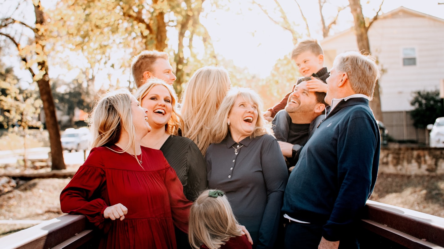 Family laughing together on an outdoor bridge.